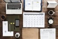 A Workspace With a Computer, Calendar, Workbook and Clock - Kathbern Management Toronto Recruiting Agency