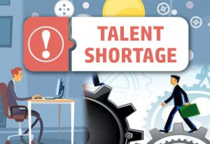A Sign Reading Talent Shortage With An Employee At a Desk - Kathbern Management Toronto Executive Headhunters